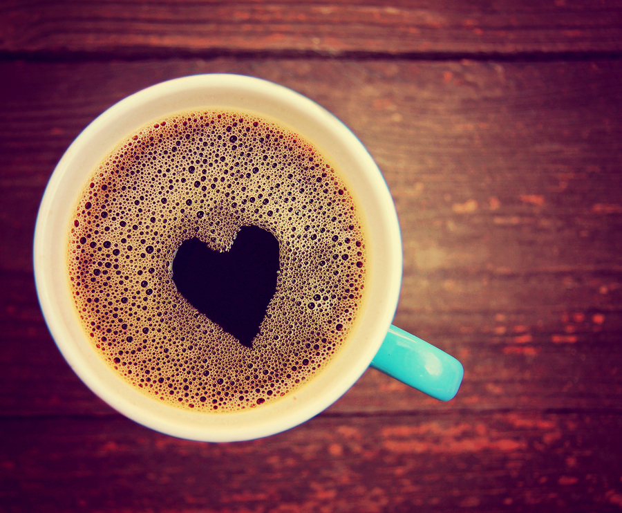 a cup of coffee with a heart shape toned with a retro vintage instagram filter 