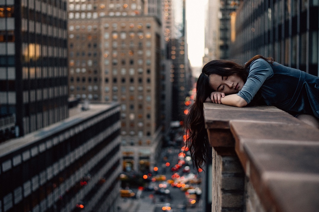 Woman lays head on edge of rooftop