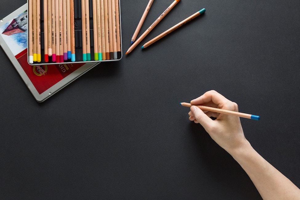 A hand holds a colored pencil, ready to begin drawing