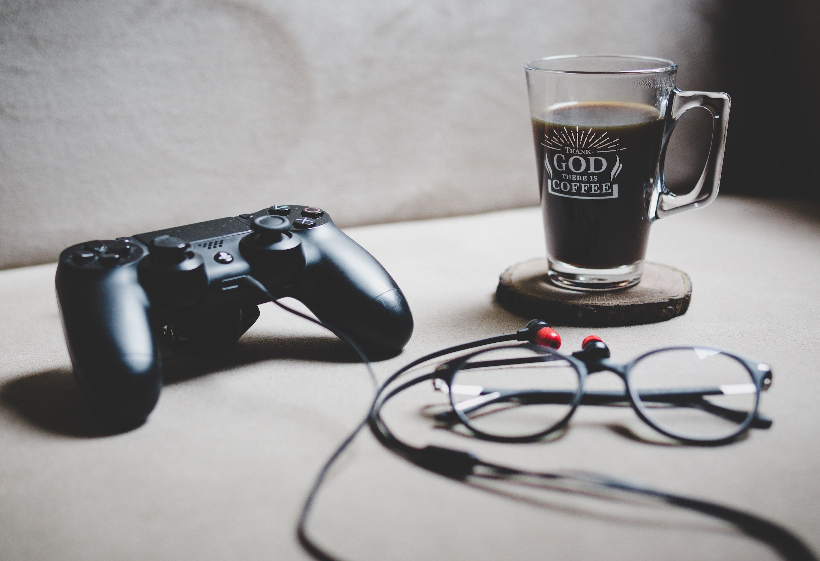Coffee, glasses, headphones and game controller sitting on a desk
