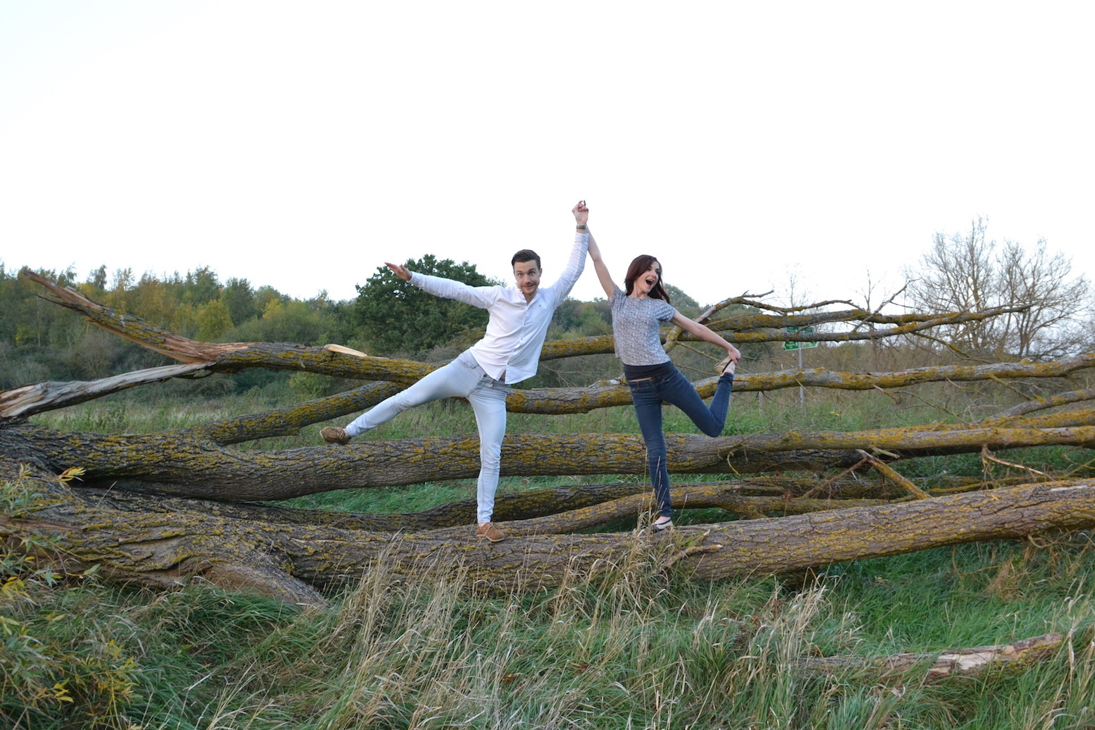 Man and woman striking silly pose by trees