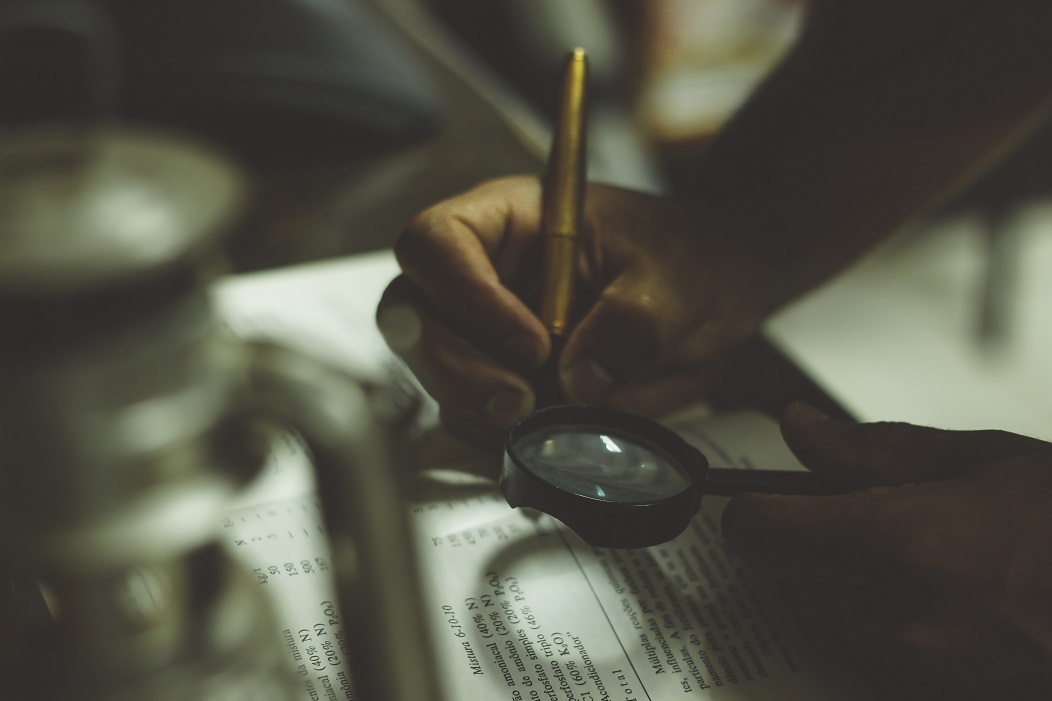 Image of a man reading a book with a magnifying glass