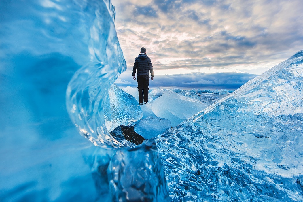 Image of a man standing on an ice formation and looking out