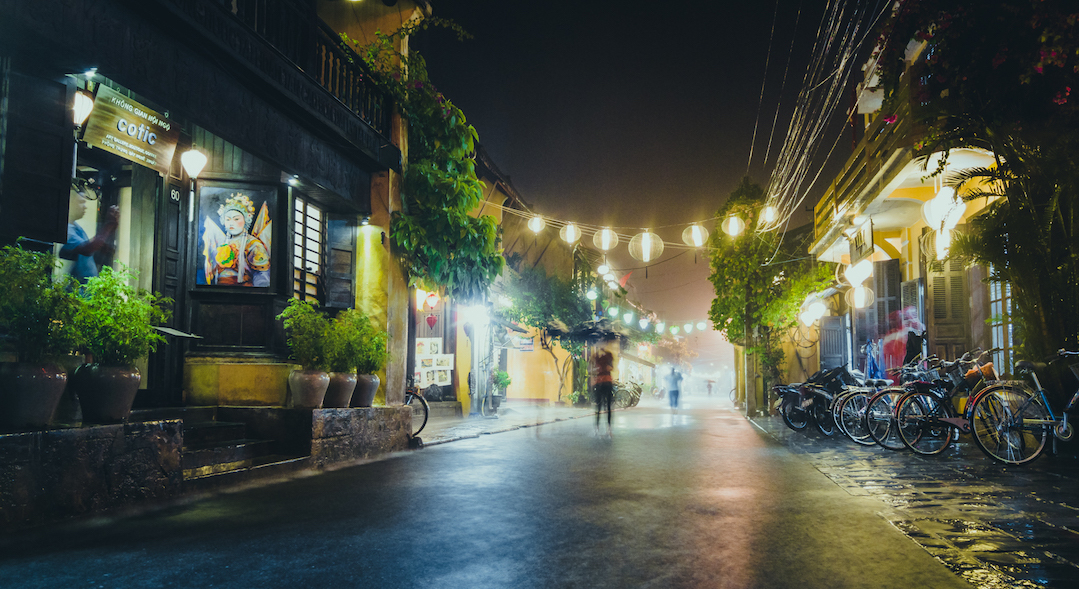 A street corner in the rain with some hanging paper lamps