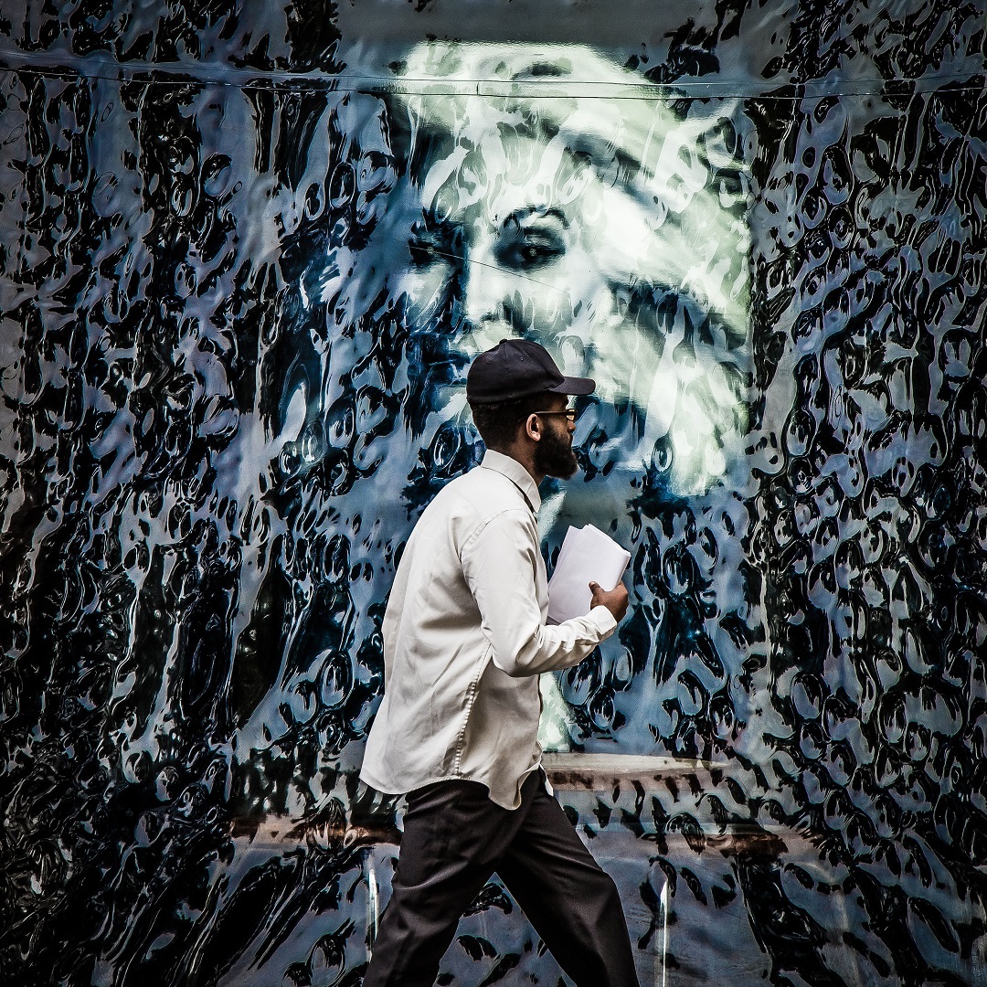 Man with papers walks past an elaborate mural