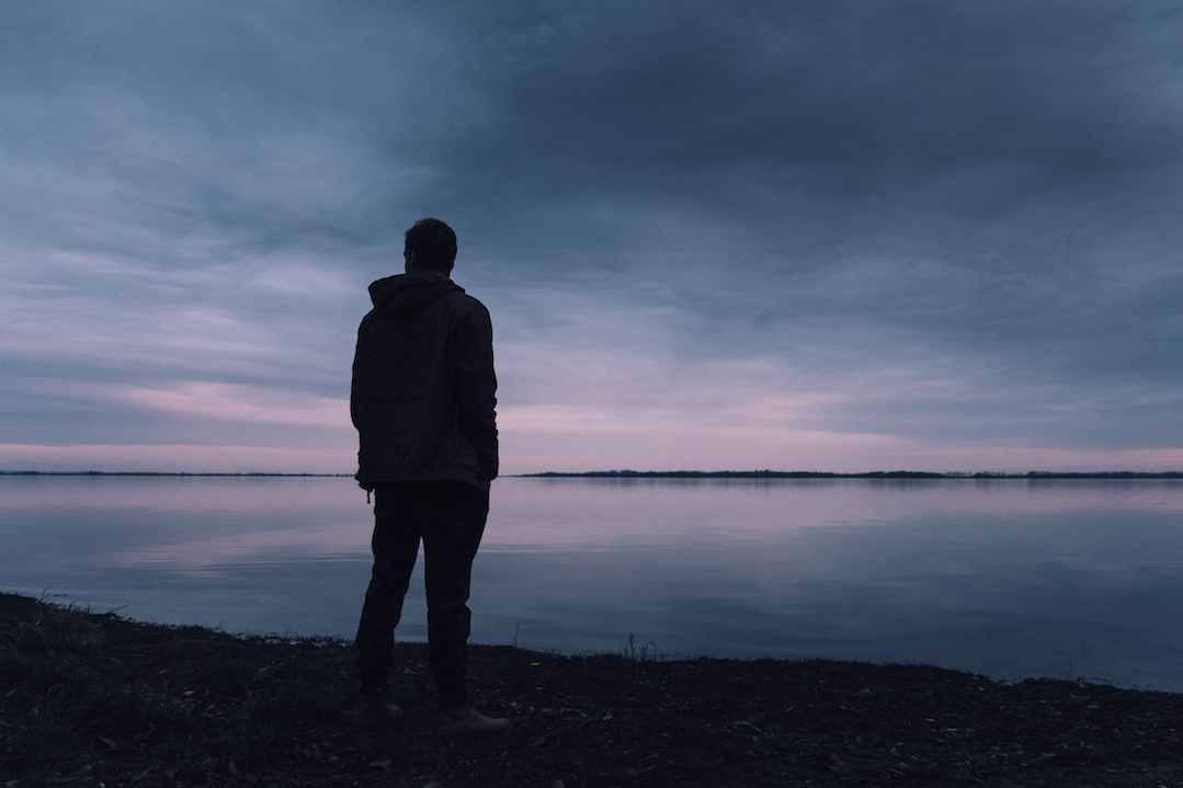 A man observes the early dawn from the beach