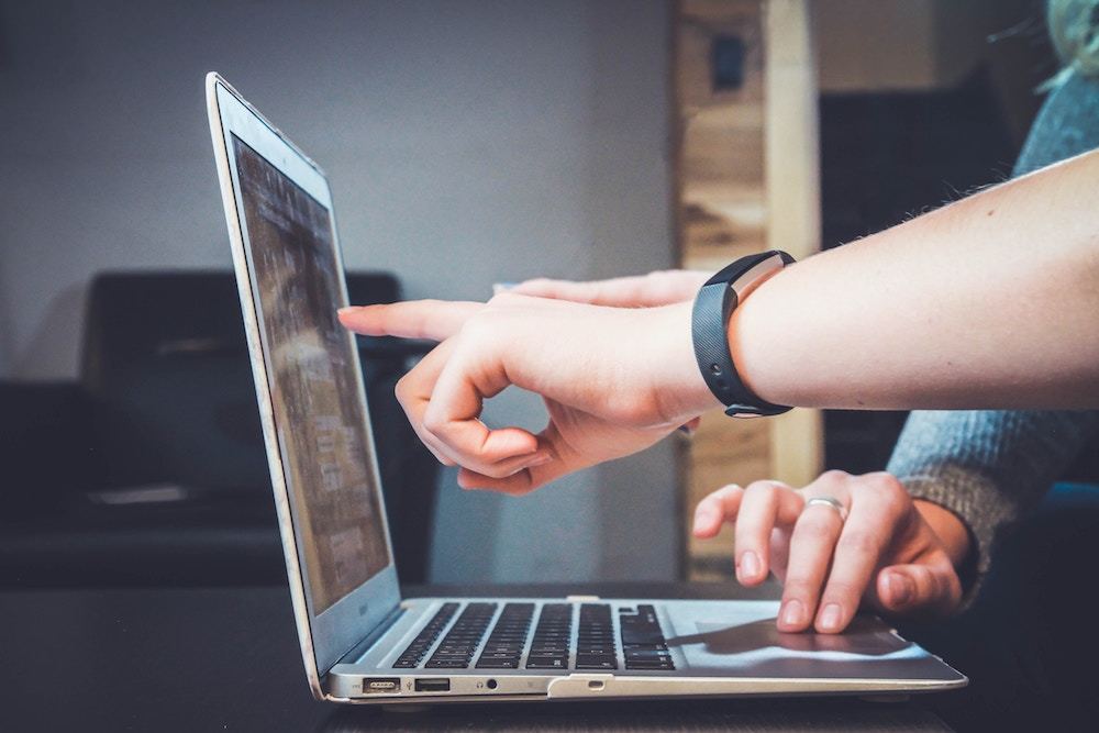 Someone points to the screen of a laptop