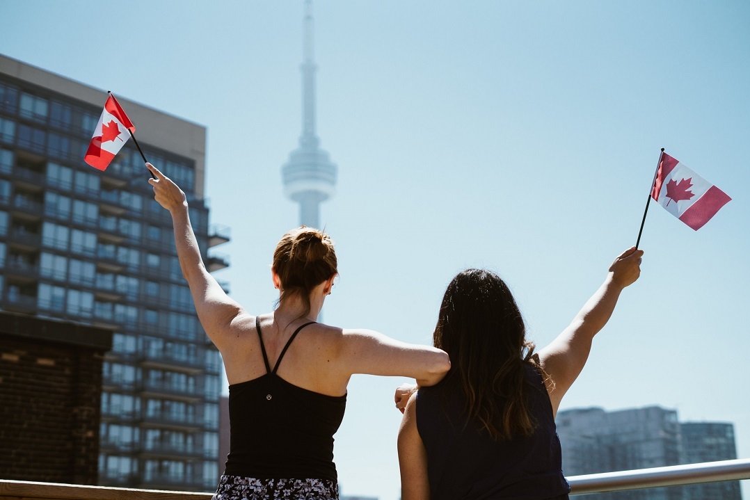 Two women waving Canadian flags