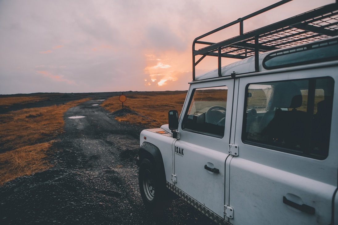 land rover on remote road with sunset in backdrop