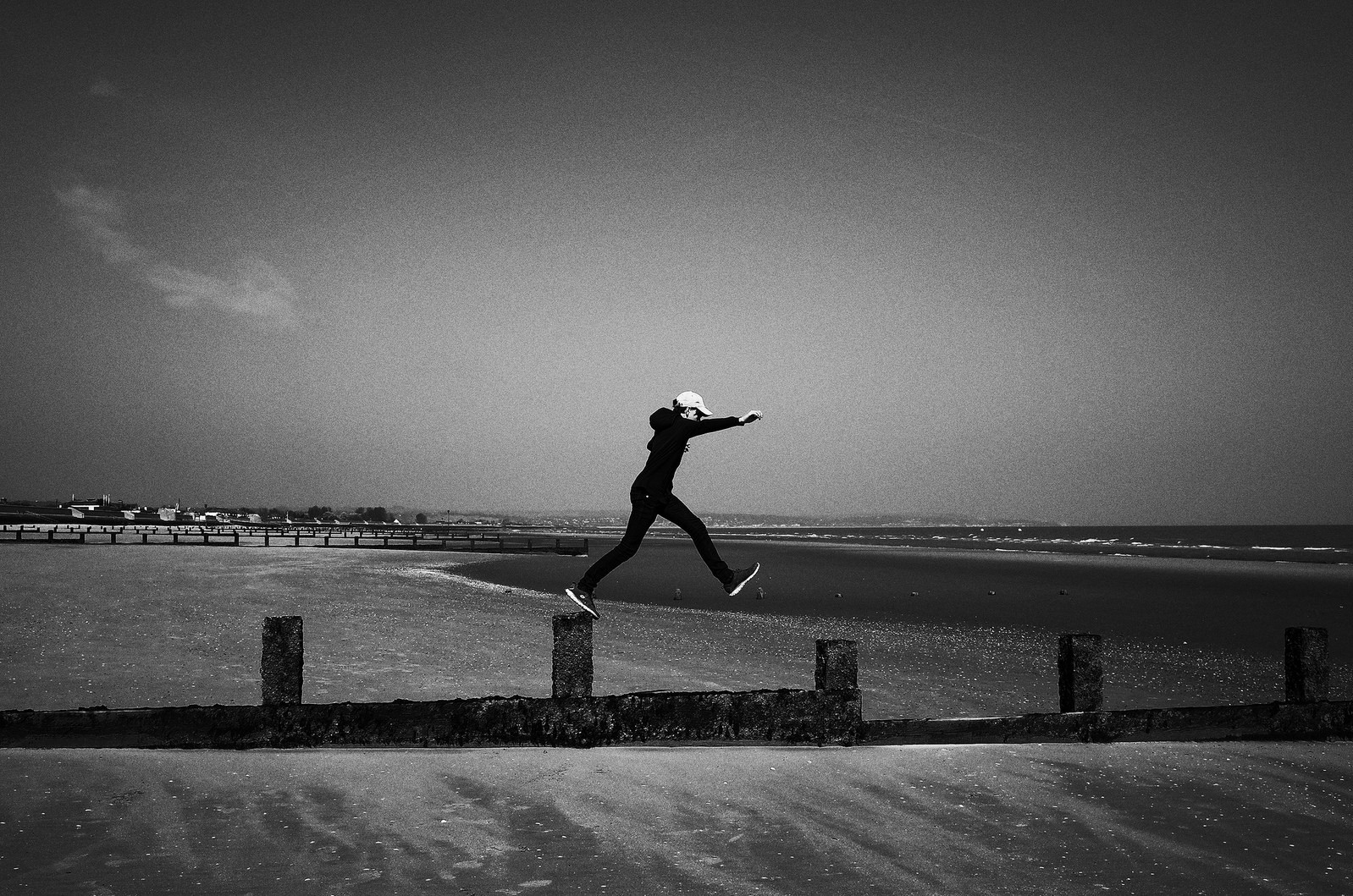 A man jumps along a pier on the shore