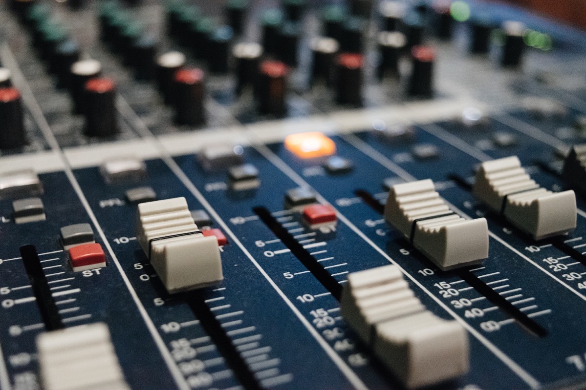 A close-up of an audio mixing board