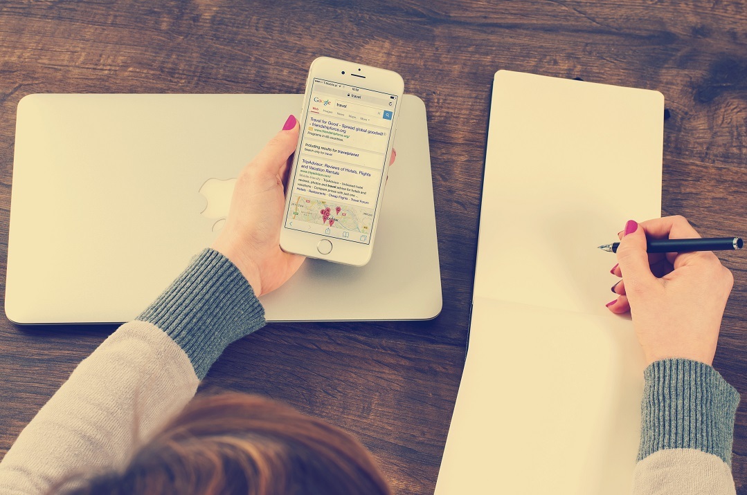 A marketer reviews search results and writes notes in a notebook