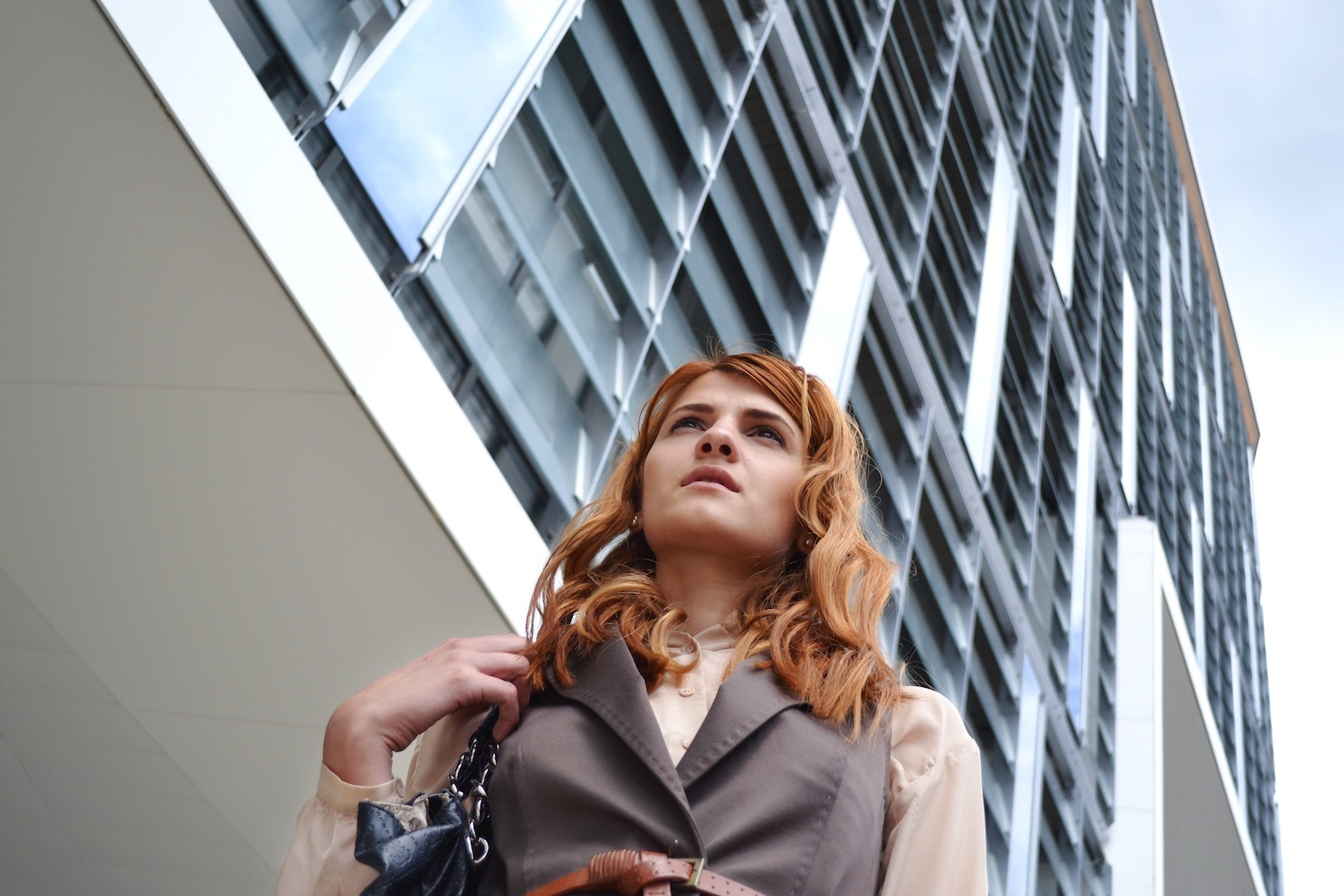 A woman in professional dress outside an office building, shot from below