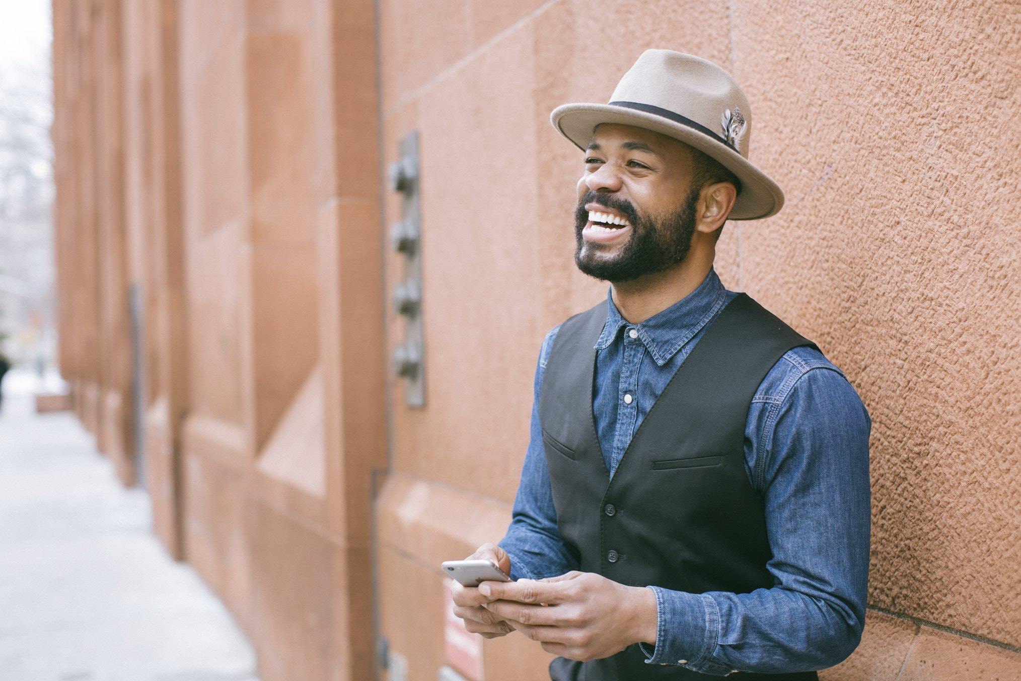 Man laughs while holding cell phone