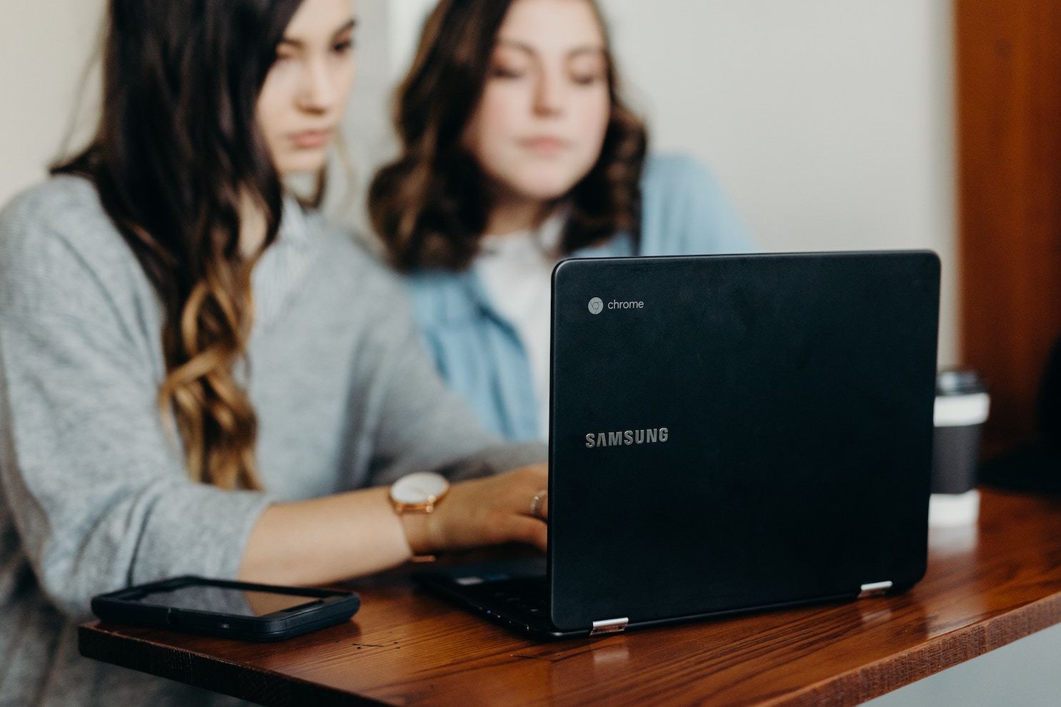 two women look at a laptop together