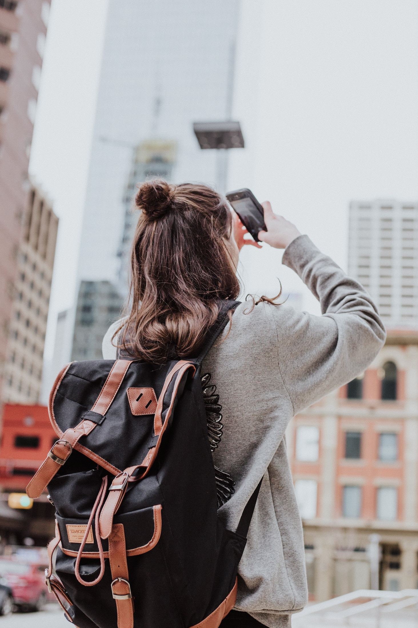 A young woman explores a city, taking pictures with her smartphone