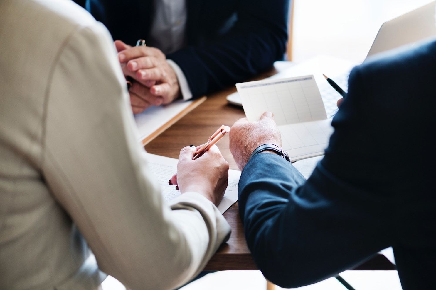 three businessmen converse around a table