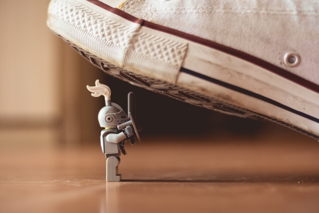 Macro shot of a shoe stepping on a small toy knight