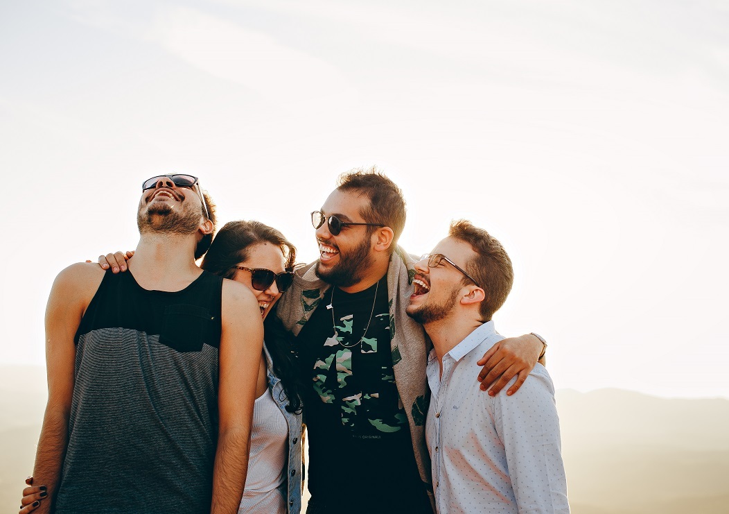 Four friends on a beach, laughing.