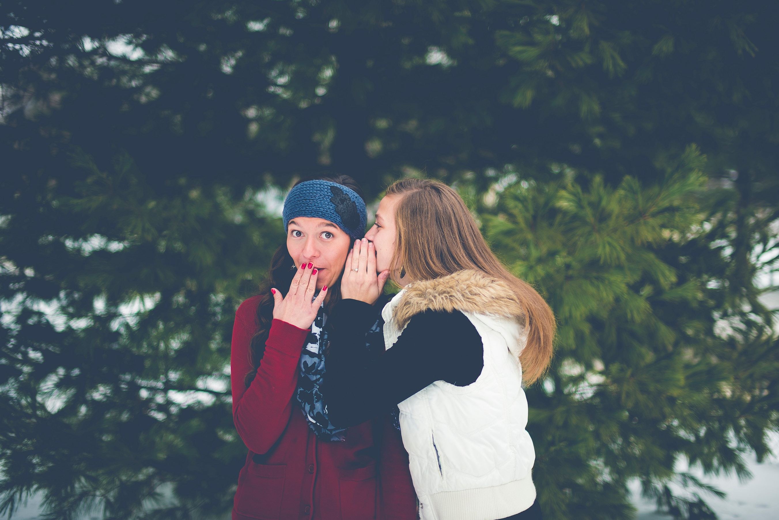 One girl whispers in another's ear