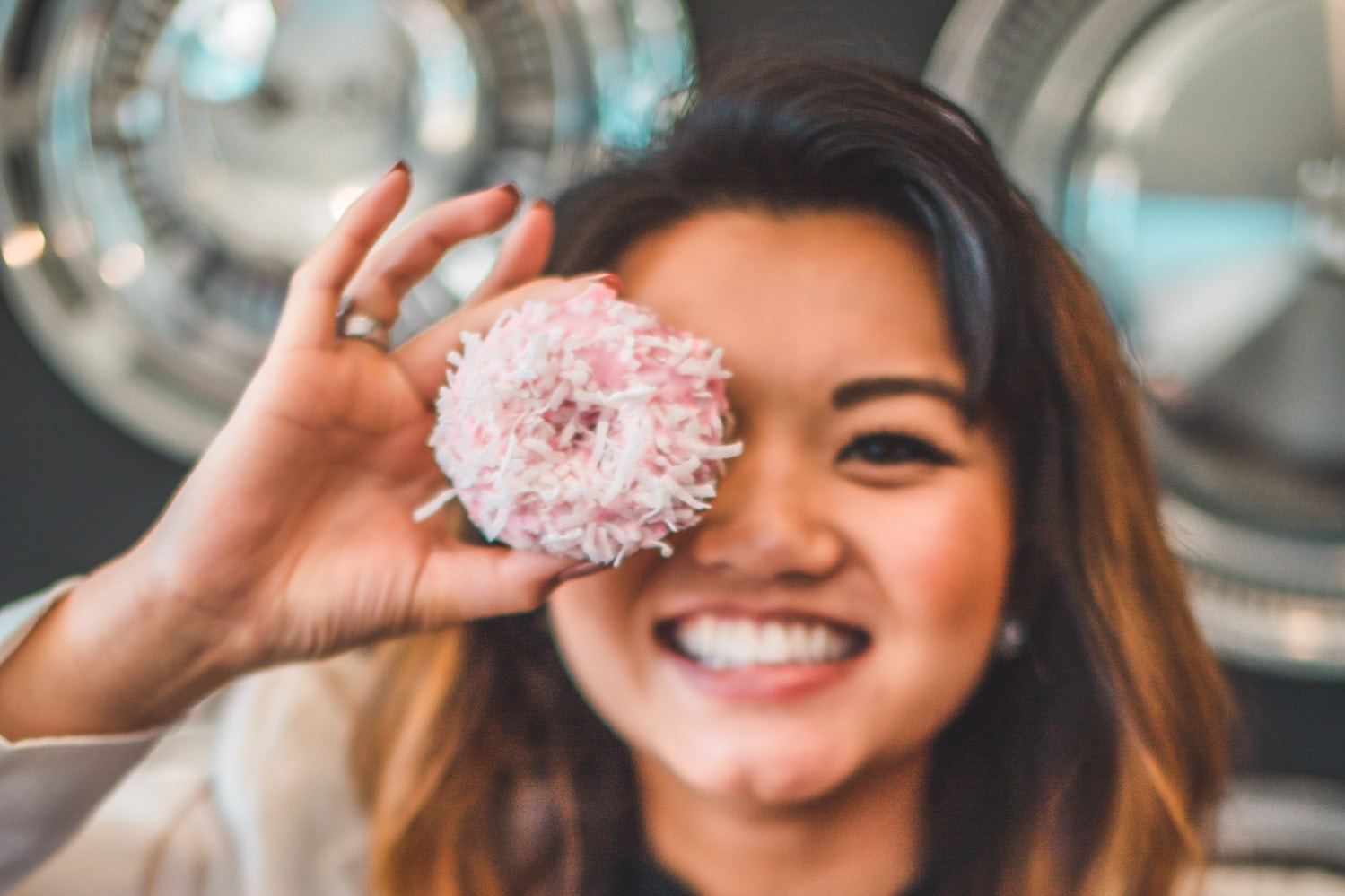 a woman poses with a pink donut
