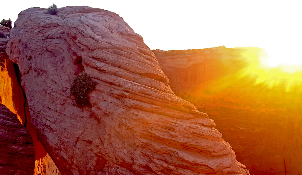 A dramatic view of the sunset over a rock arch in the desert