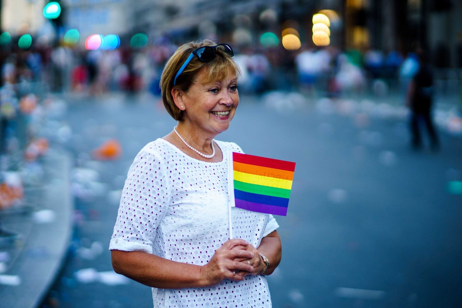 A woman holds a small rainbow flag in the aftermath of a parade
