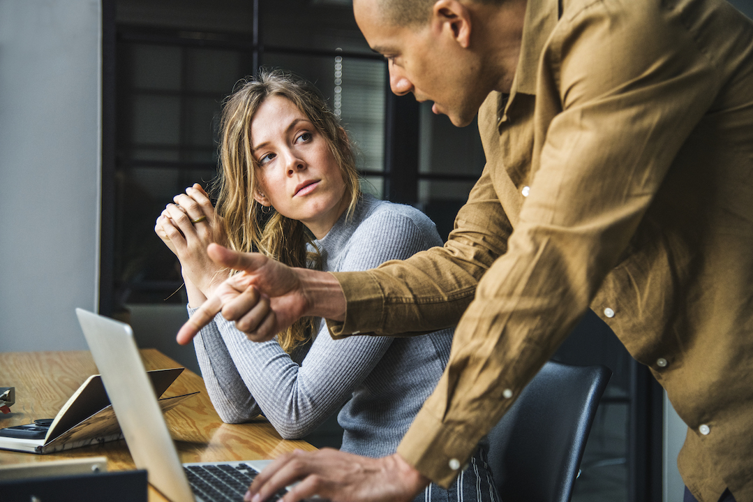 Two coworkers discuss over a laptop