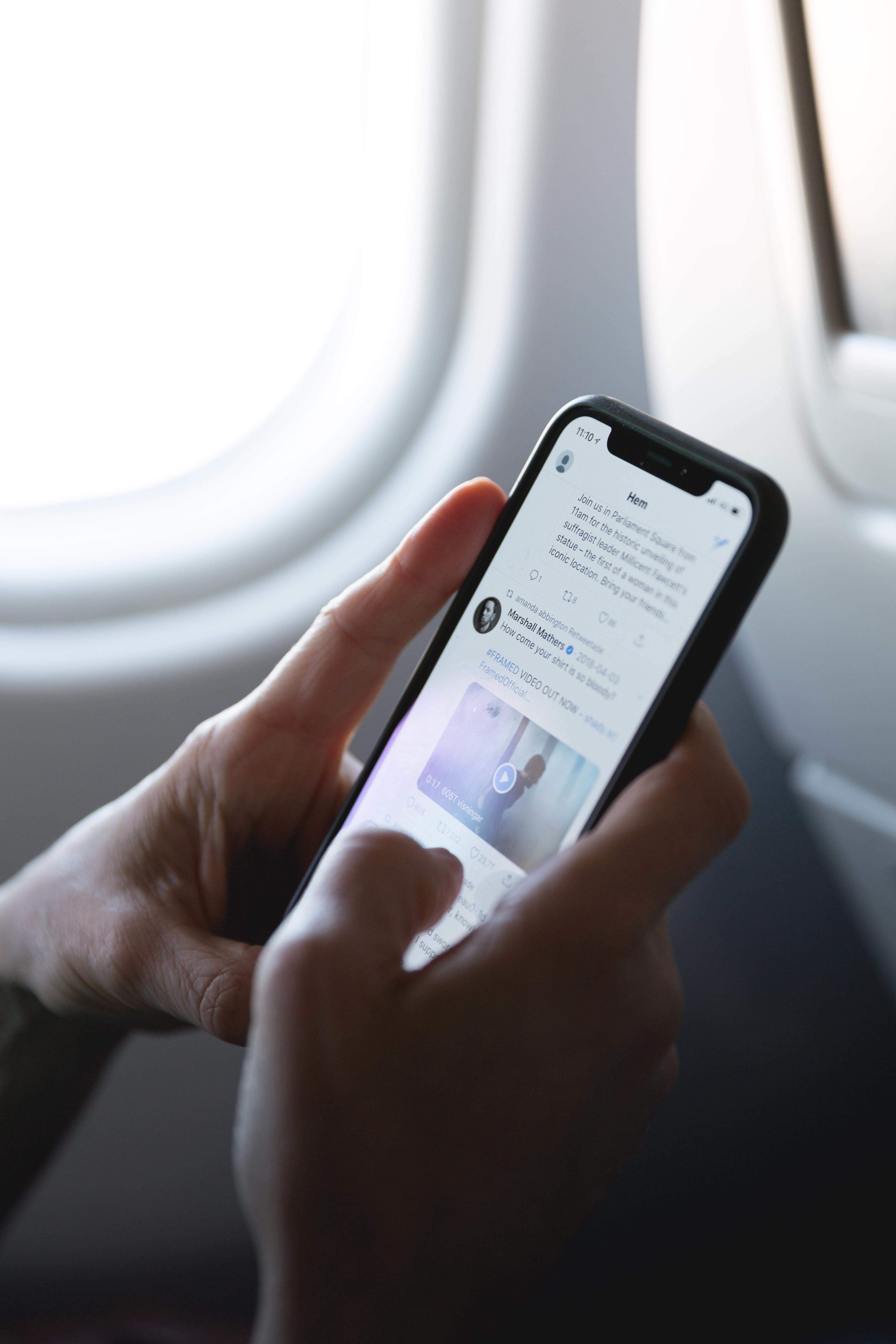 man checks Twitter on plane