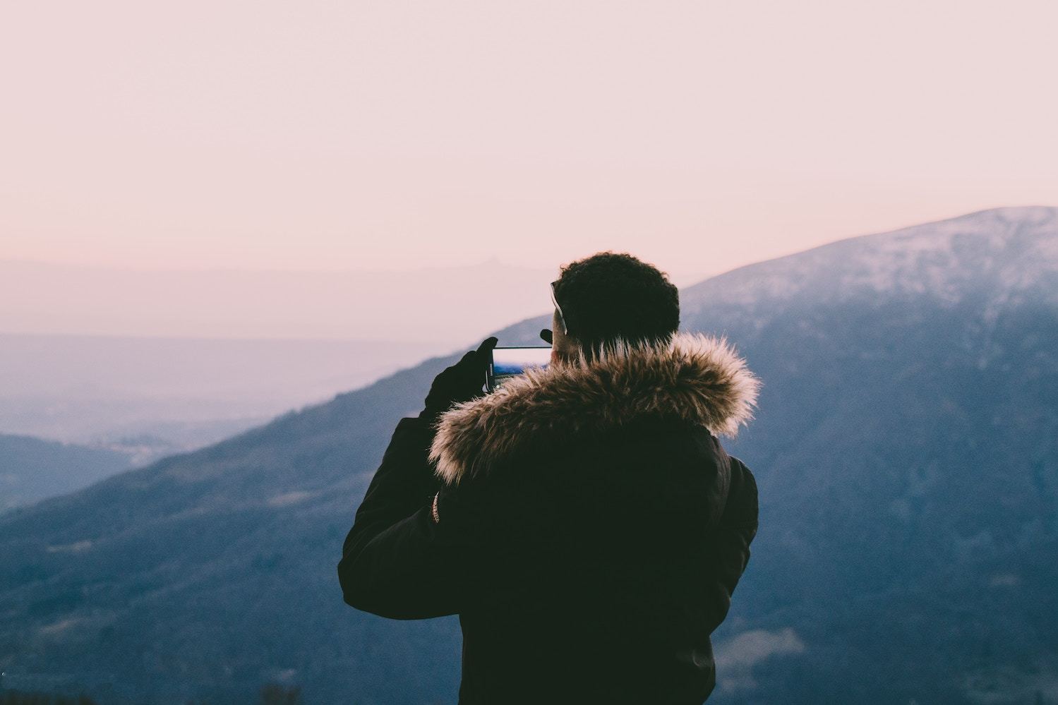 A man takes a photo from atop a mountain