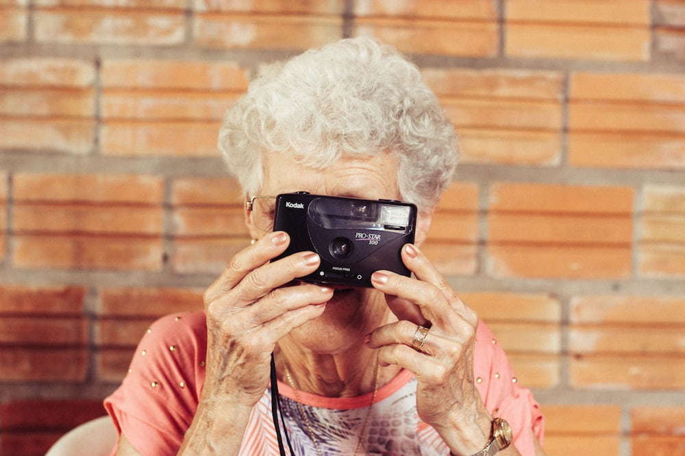 Elderly woman holding a camera defies age-based market segmentation
