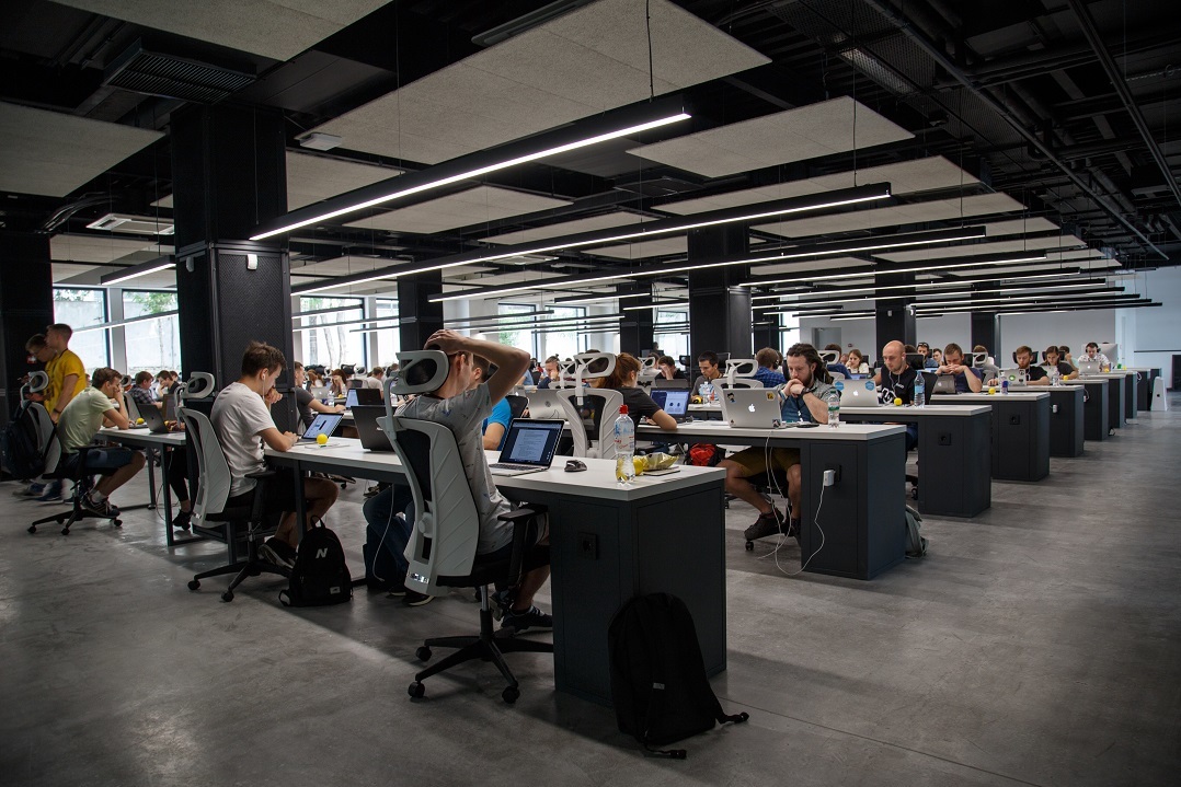 A large team of marketers works at desks with laptops