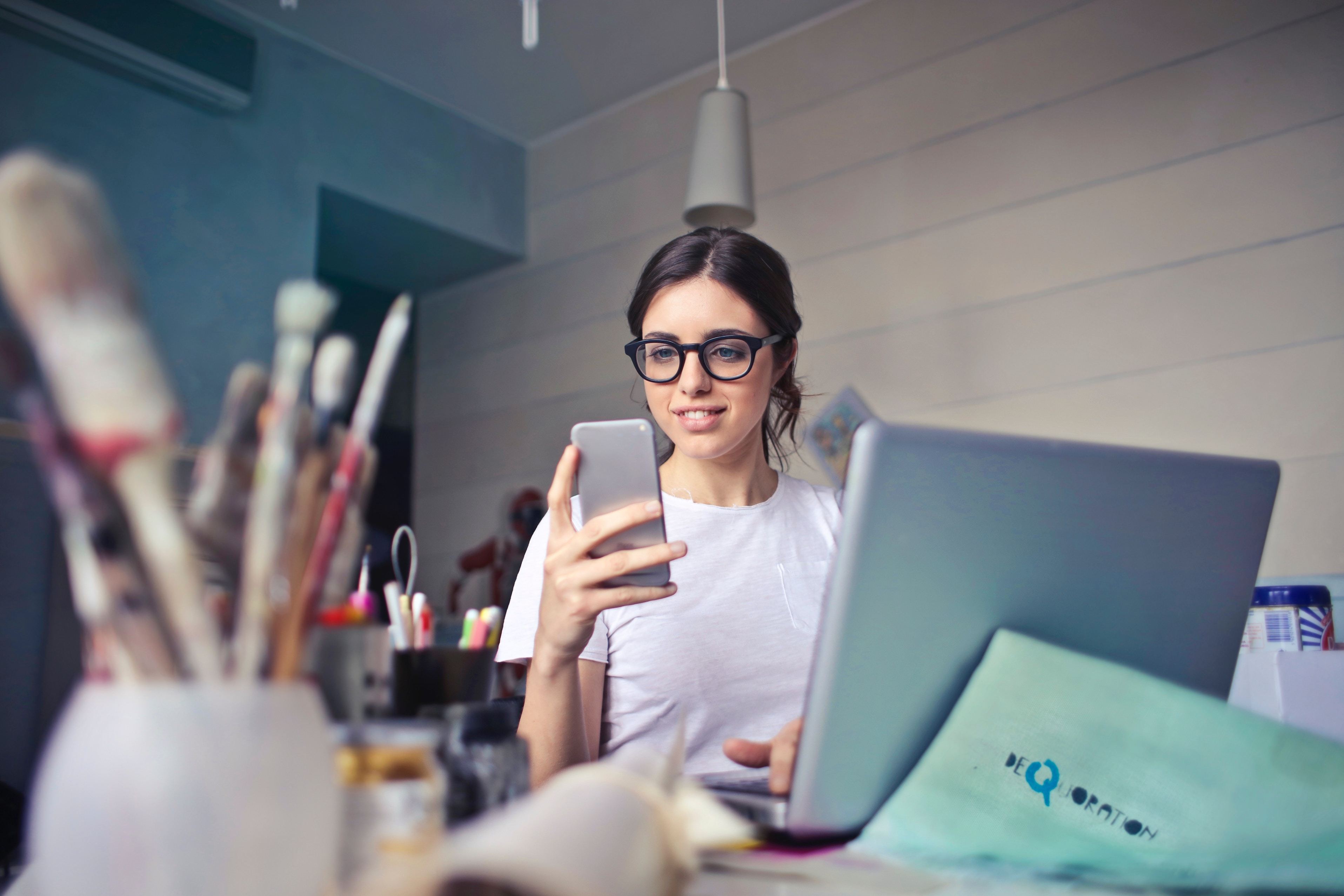 Woman at desk holding up smartphone