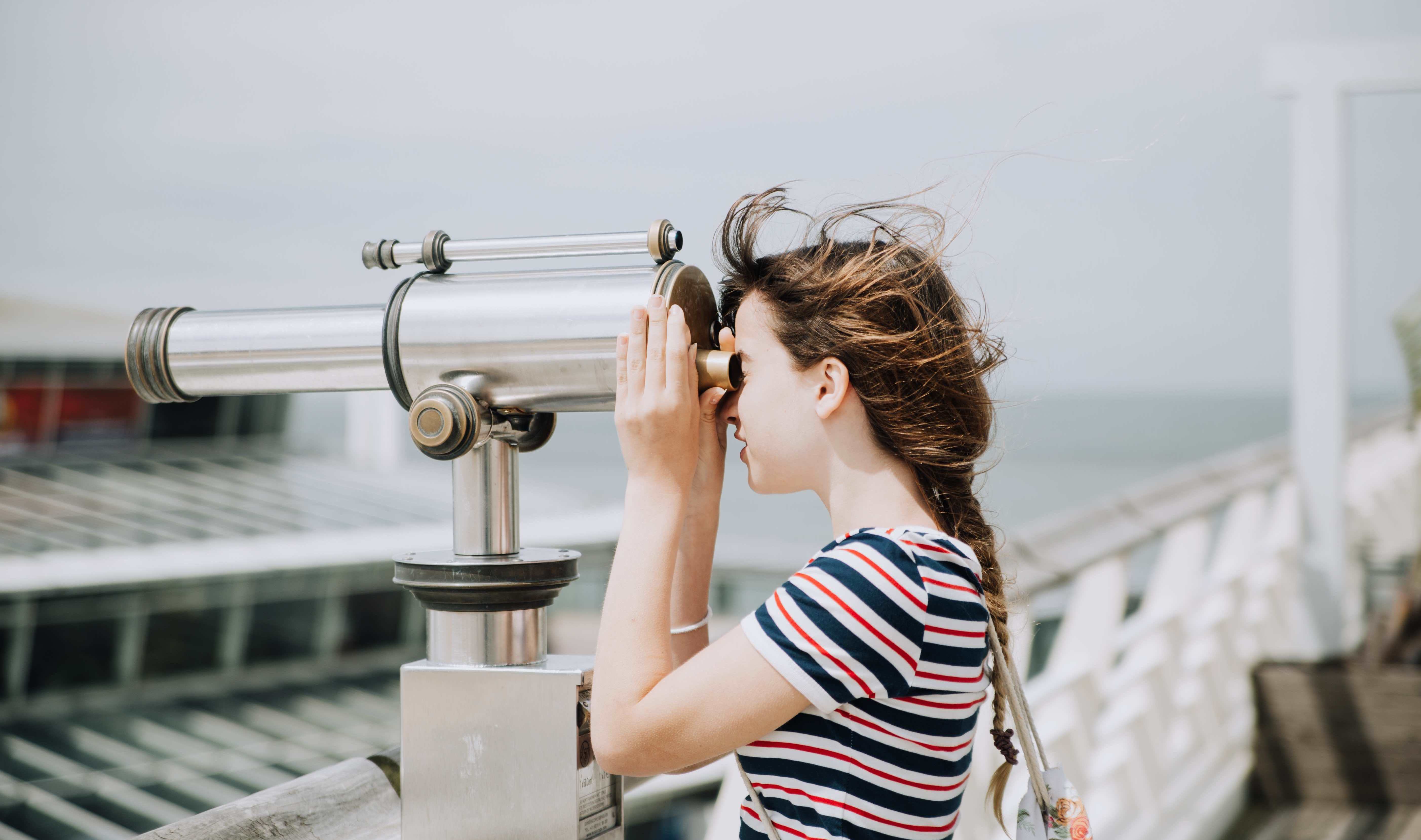 woman looking through telescope