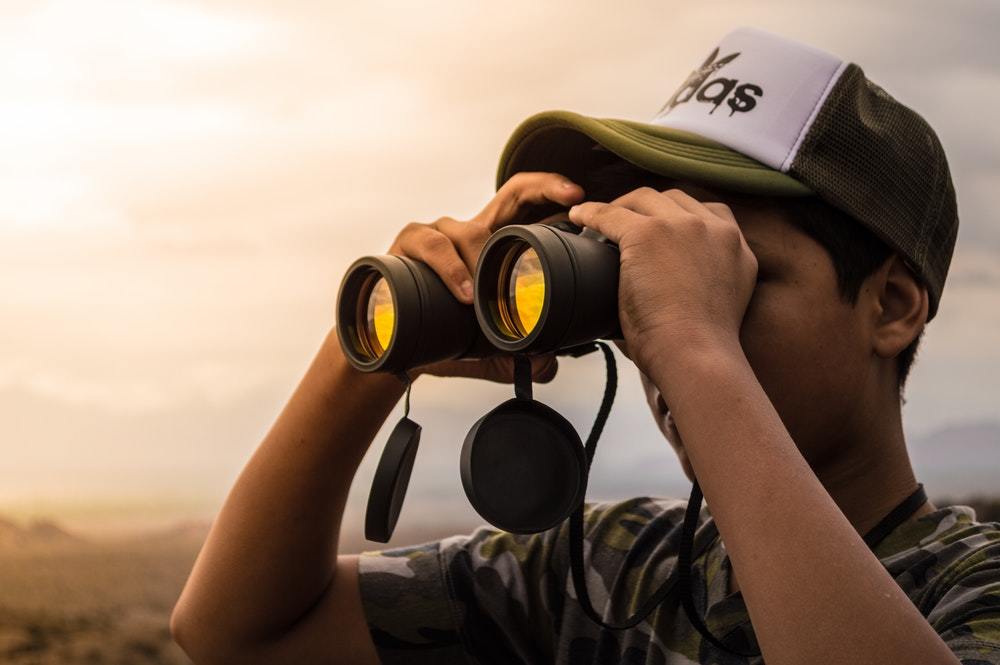 A man watches the scene at sunset through his binoculars.