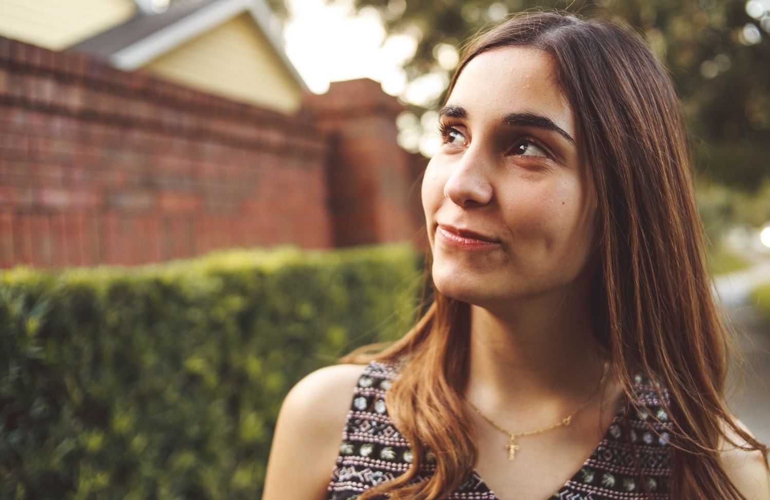 A woman smiles subtly, looking into the distance