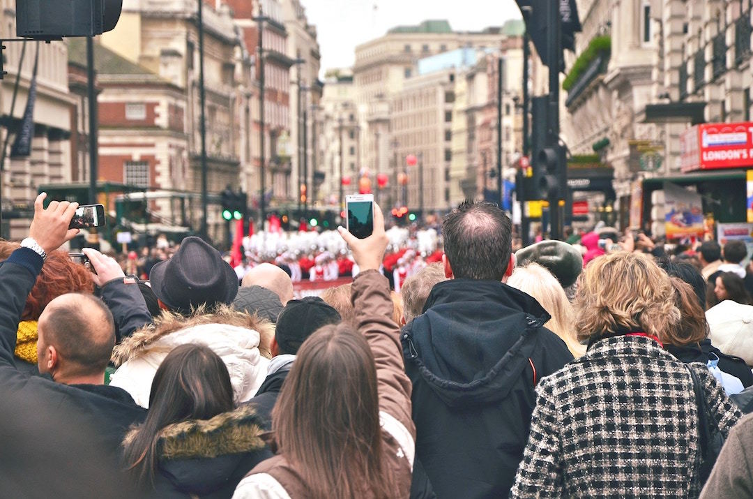 People crowd in a street to take photos with phones