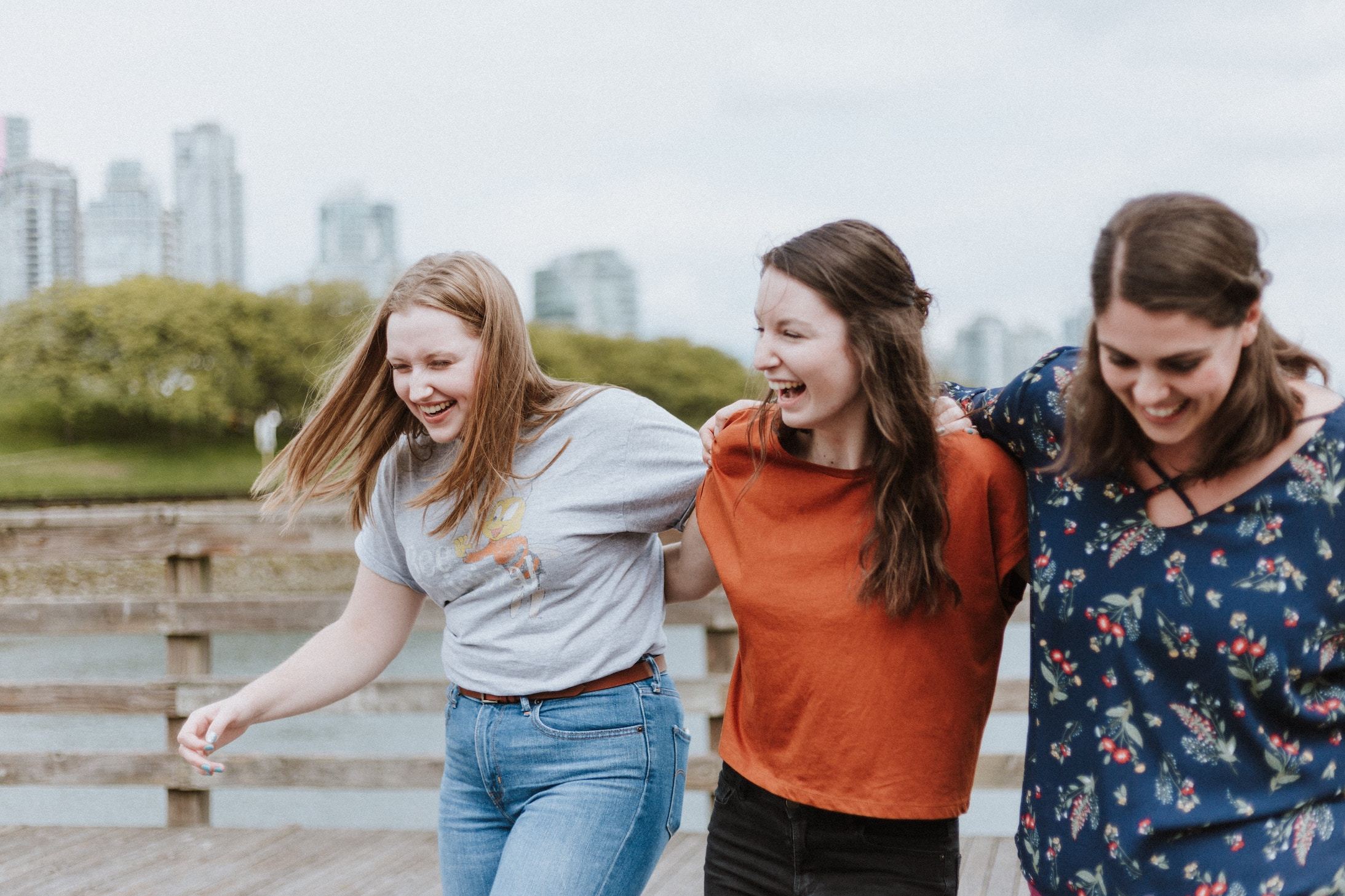 Three girls link arms and laugh