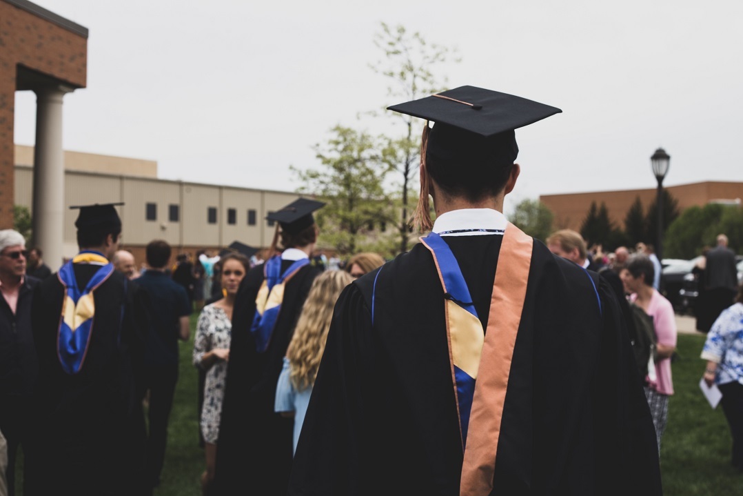 A student stands in graduation cap and gown