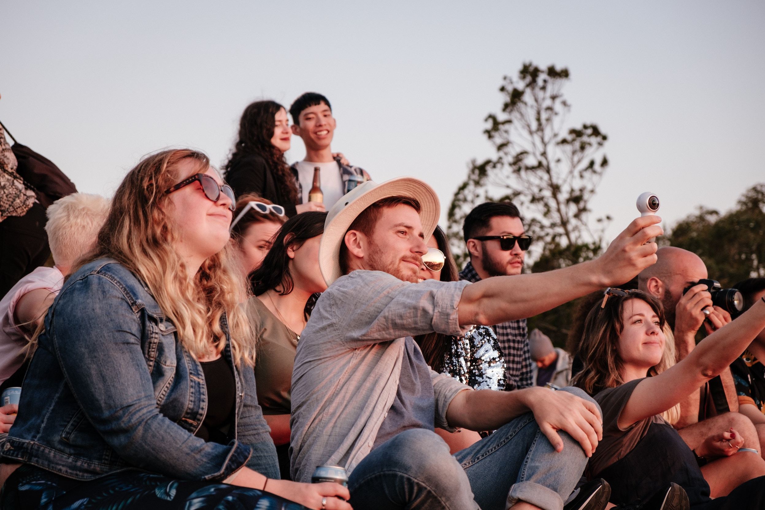 group of people sitting in nature recording a sunset