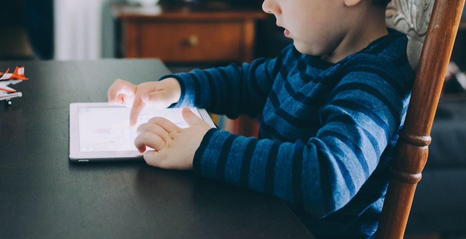 boy plays with tablet at kitchen table