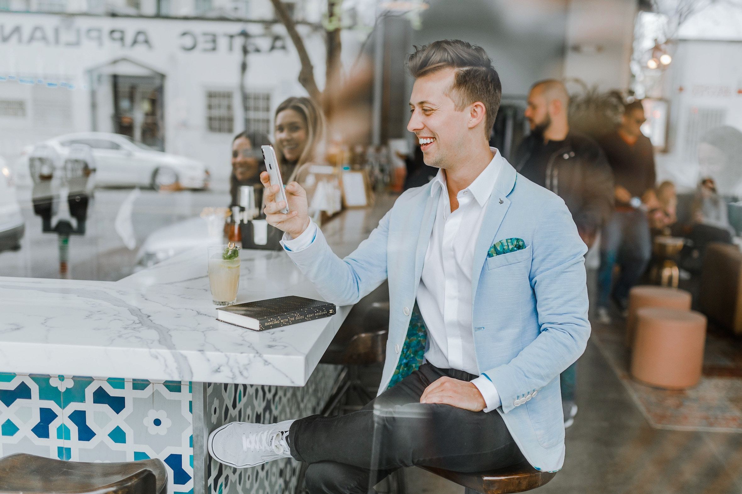 Smiling man sitting at counter reading something on smartphone