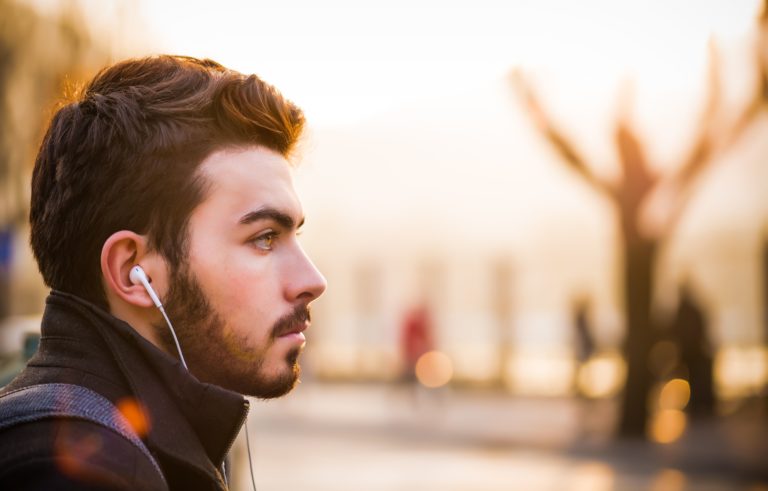 Man listening to a podcast with his smartphone while he stares off into the distance.