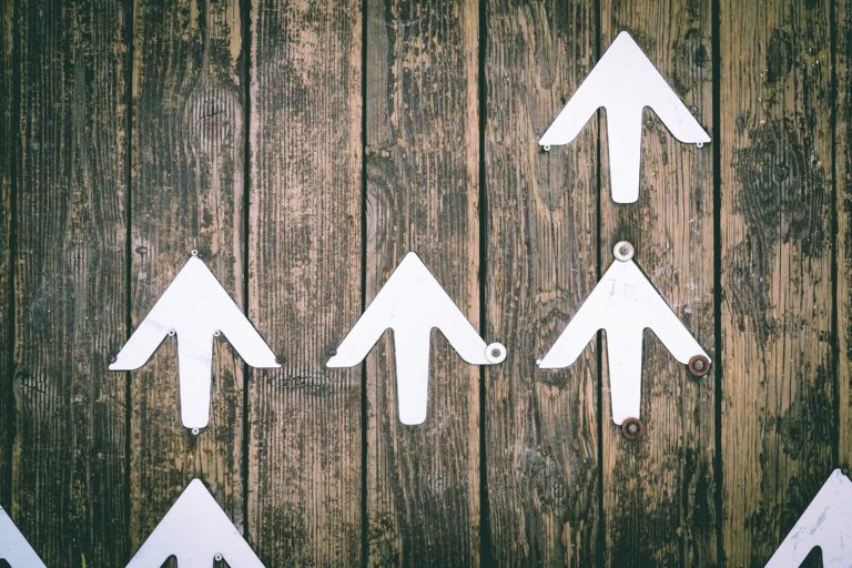 White arrows on a wooden board indicate the success potential of LinkedIn ad budgeting.