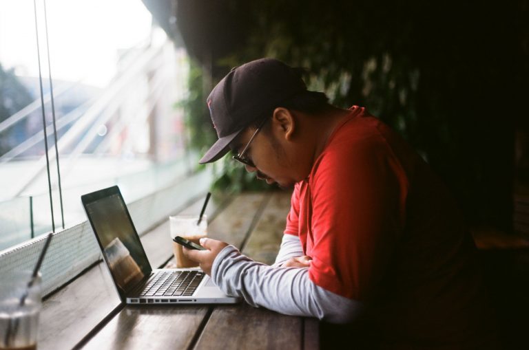 A man looks at his smartphone while sitting at a coffee shop.