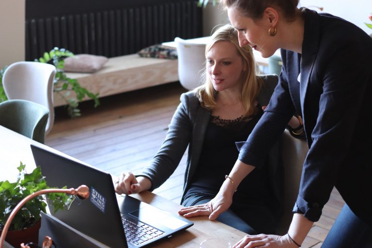 Two female business leaders looking at a laptop screen in an office