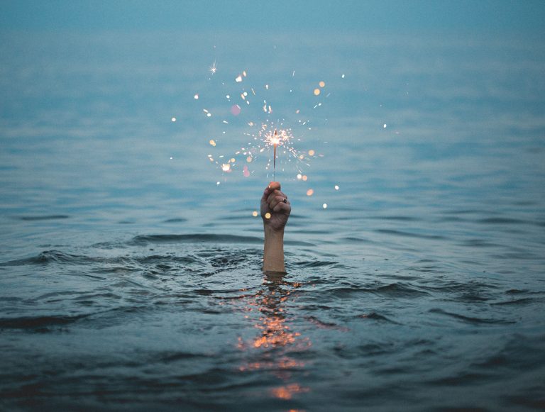 Hand emerging from water, holding a sparkler