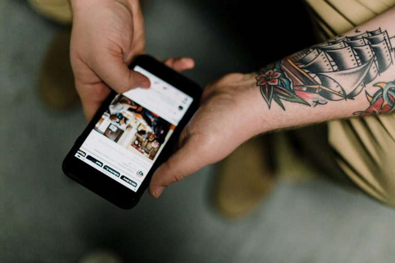 A man with tattoos looks at content on his mobile device that's driven by SEO changes in 2019