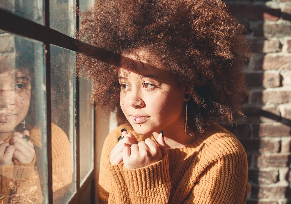 A woman on a remote marketing team stares out a window with a look of uncertainty during the coronavirus pandemic.