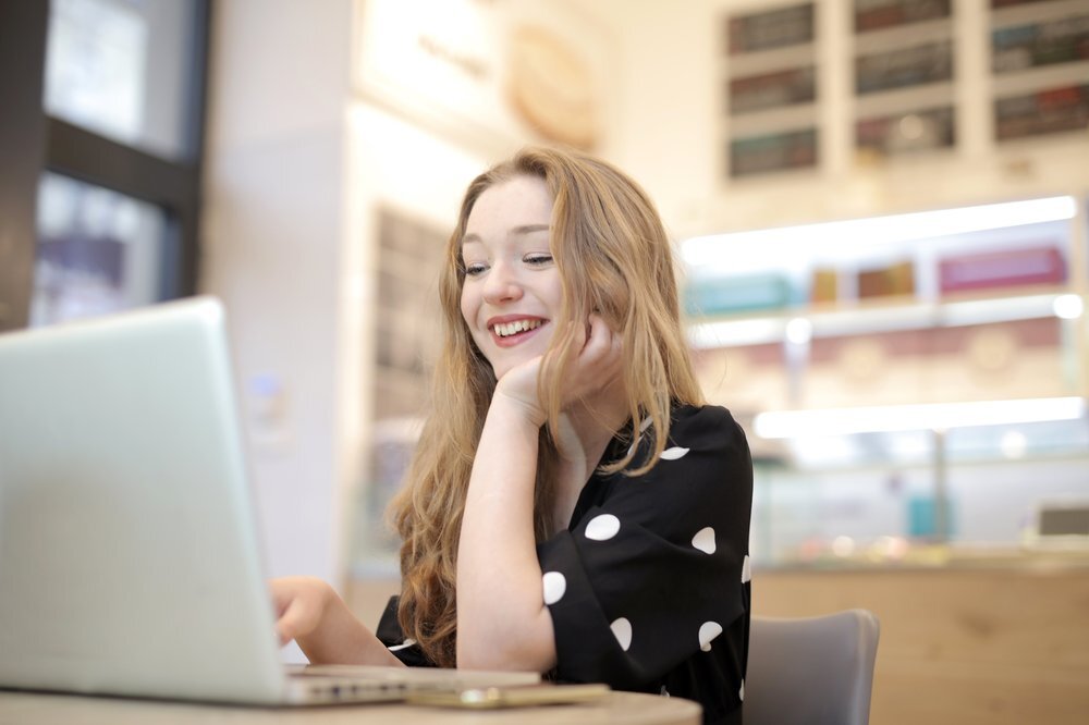 Woman in black and white polka dot dress sitting on chair looking at content marketing posts.